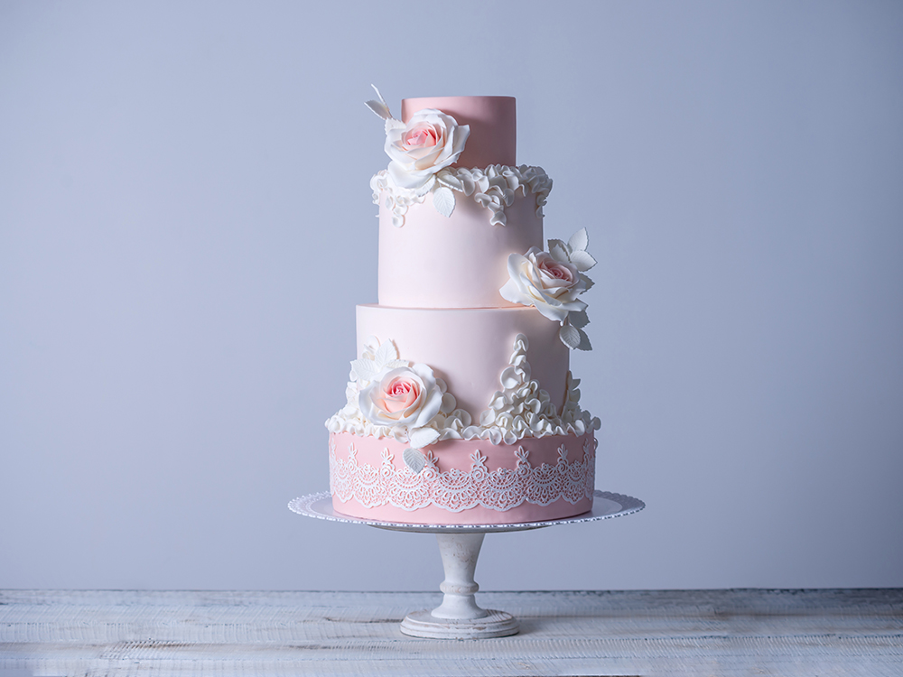 Beautiful elegant four tiered pink wedding cake decorated with roses flowers. The concept patisserie floral from sugar mastic